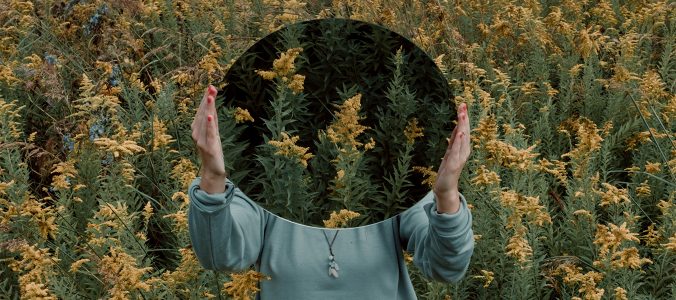 Women holding mirror blocking face
